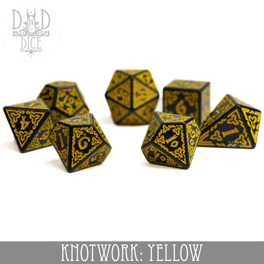 Yellow acrylic 7-dice set with Celtic knotwork and teardrop D4 on a white background.