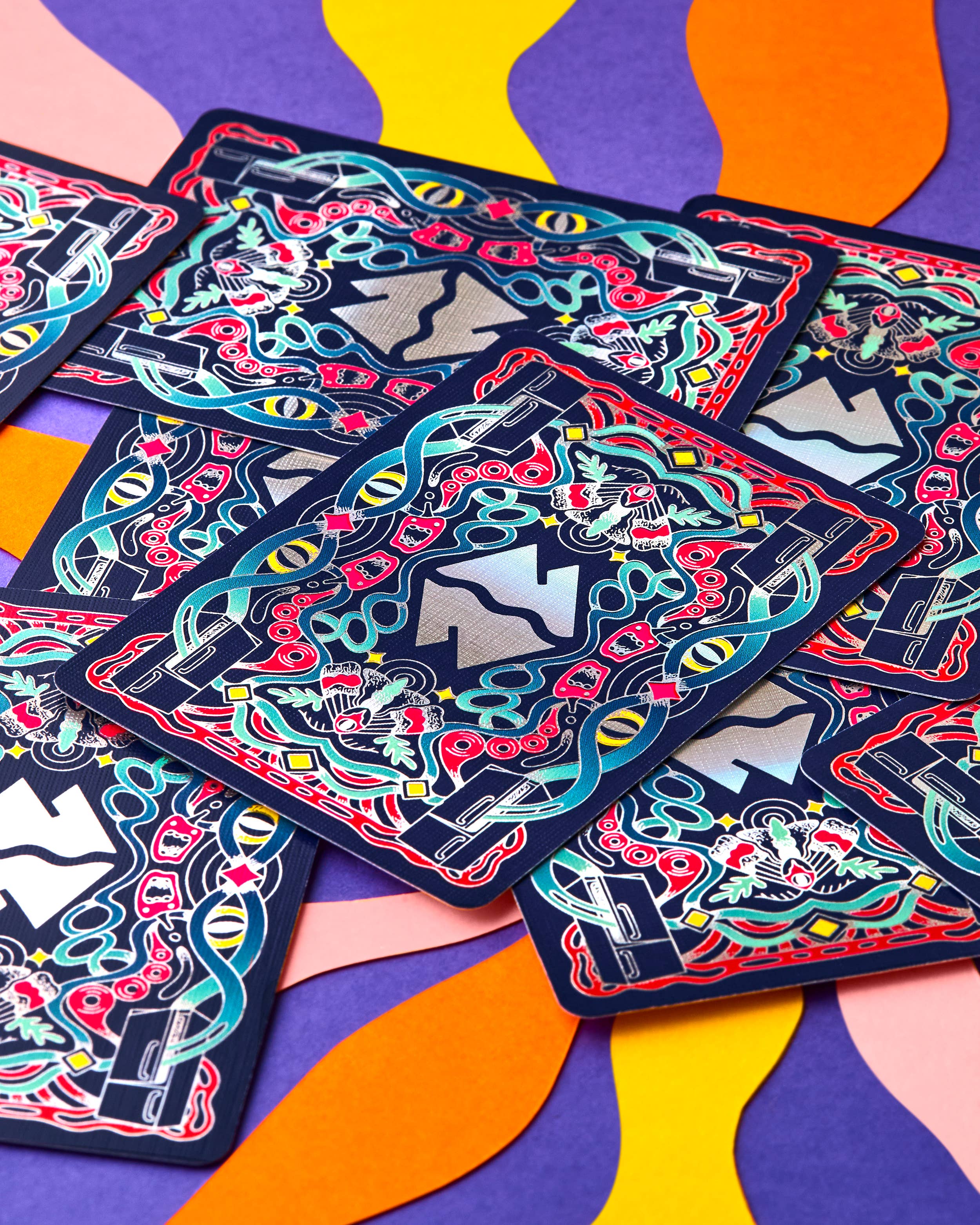 Meow Wolf playing cards with colorful eye, flower, and ribbon illustrations.