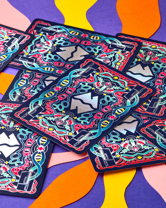 Meow Wolf playing cards with colorful eye, flower, and ribbon illustrations.