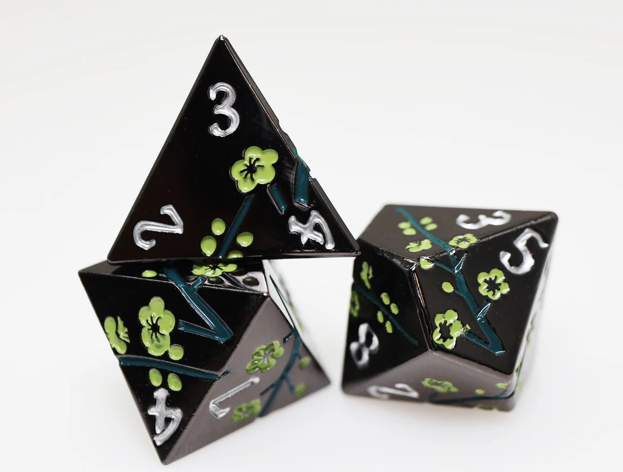 Three black triangular dice with white numbers and a green flower, from the Metallic Bouquet: Dark Green Hellebore set.