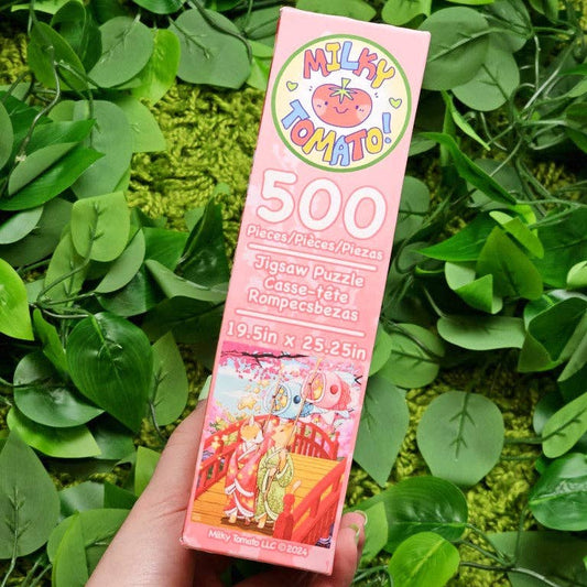 Kimono Kitties 500-piece puzzle box held in a hand, showing art with green leaves and kitties.