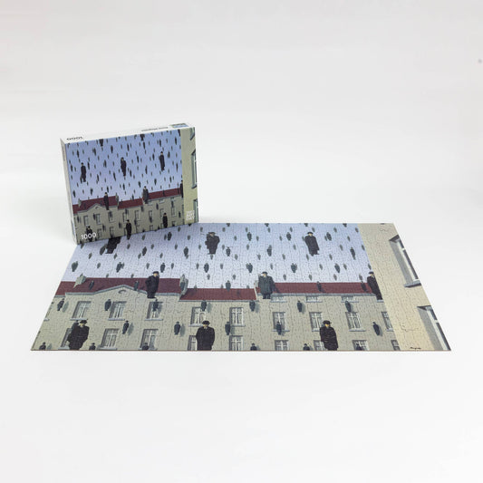 René Magritte Golconda 1000-piece puzzle featuring men in black coats floating above buildings under a pale sky.