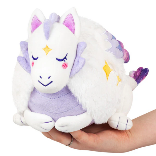 Mini Squishable Lunar Dragon plush with closed eyes, purple accents, yellow stars, and retro style held in a hand.