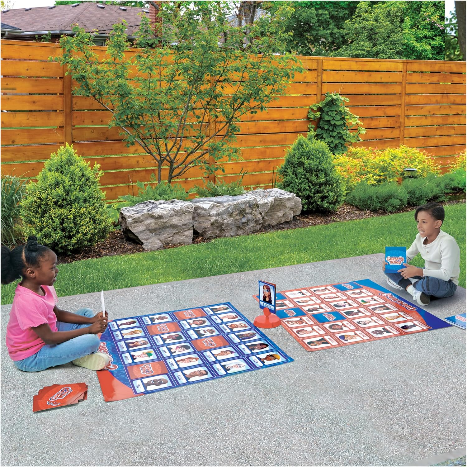 Two children playing Guess Who Giant Edition Game outdoors.