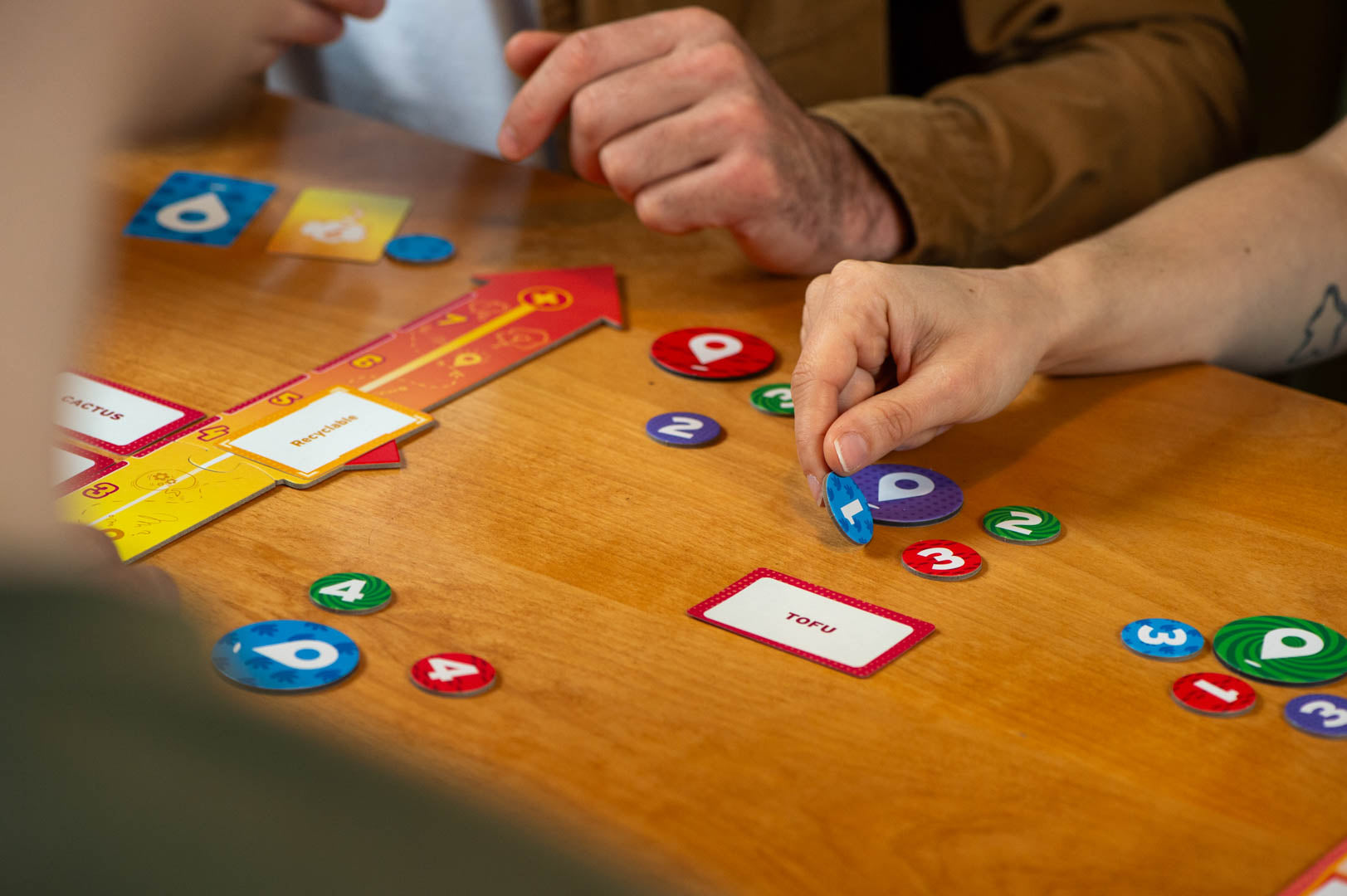 Mind Map strategy board game with colorful number tokens and cards on a wooden table in use by players.