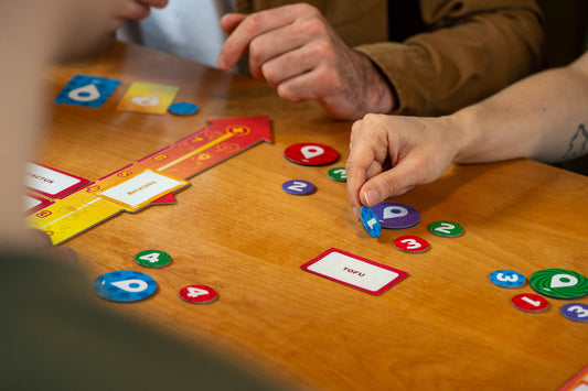 Mind Map strategy board game with colorful number tokens and cards on a wooden table in use by players.
