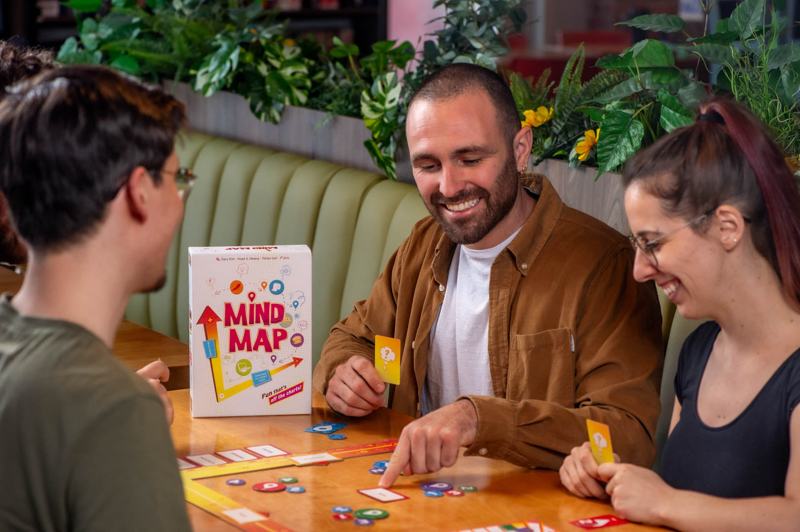 Mind Map strategy board game in use, shown with cards and tokens. Four people are playing.