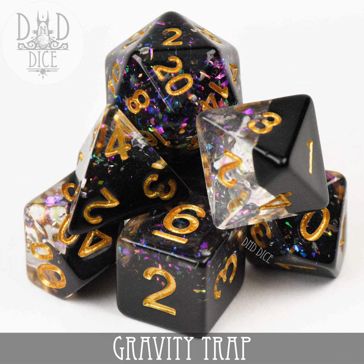 Gravity Trap 7-piece polyhedral dice set, black and clear resin with gold numbers and colorful foil.