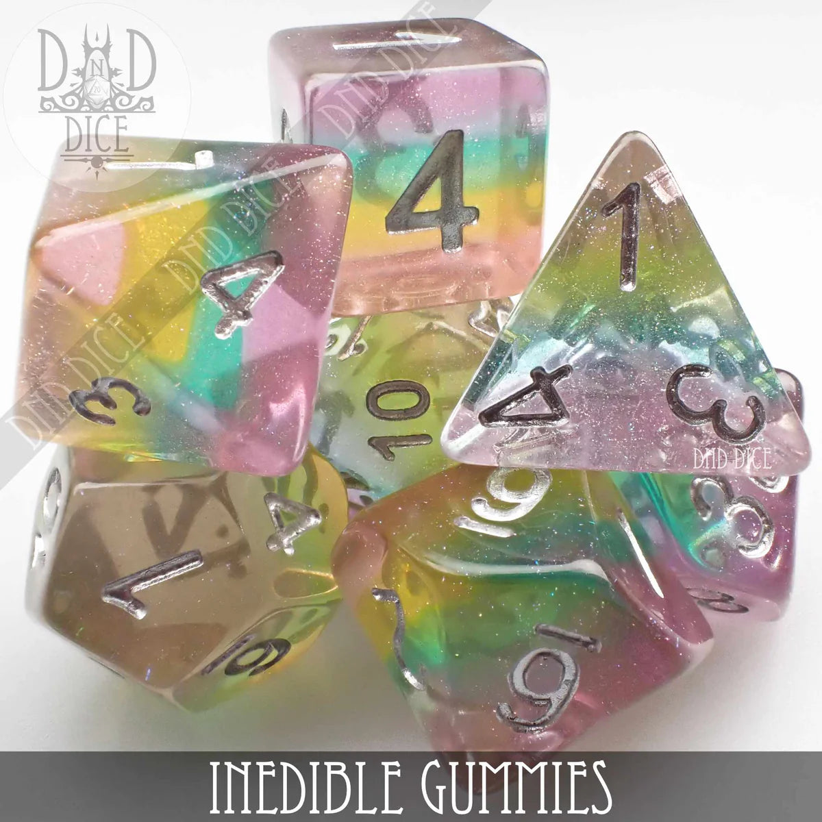 7-piece rainbow translucent resin dice set with silver numbers, labeled Inedible Gummies.