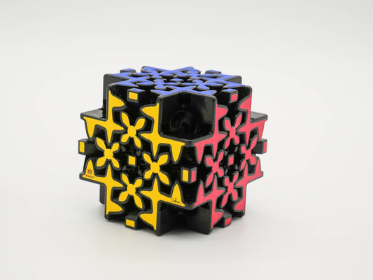 Mefferts Maltese Gear cube, black with yellow, red, and blue patterns.
