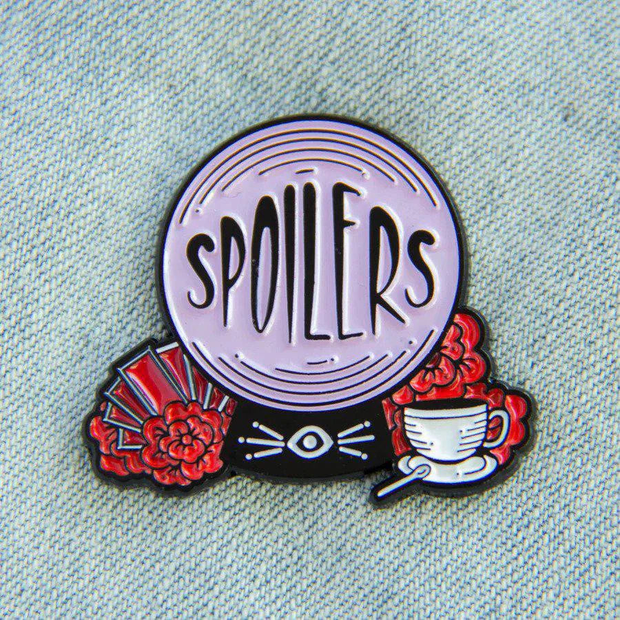 Spoilers Crystal Ball Fortune Teller enamel pin featuring red flowers, an eye, fan, and teacup on light denim.