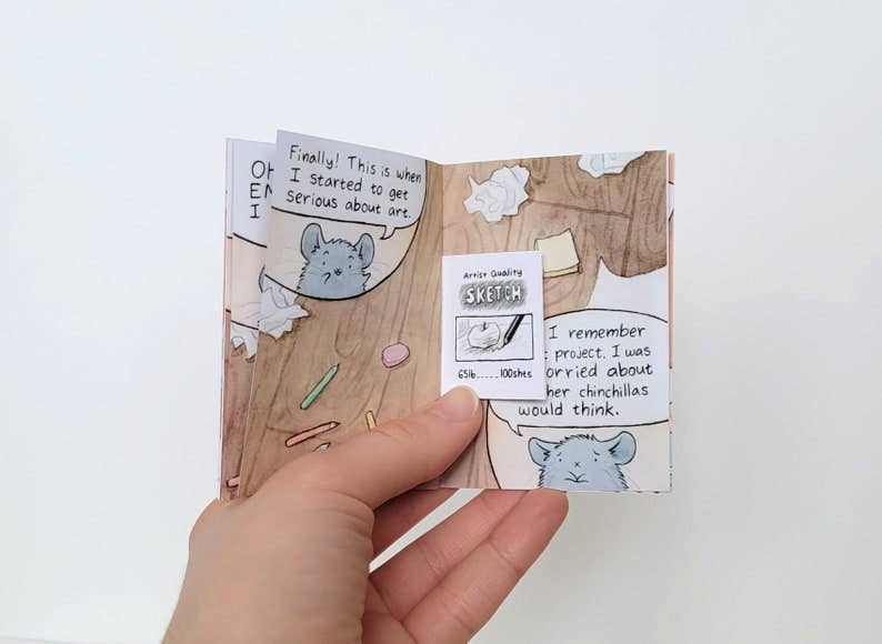 The Chinchillustrator - Mini-Comic Zine held open, displaying a chinchilla comic across two pages.
