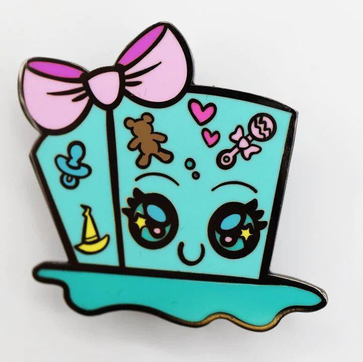 Baby Monster Pin: Gelly Cube, teal enamel pin shaped like a cartoon top hat with eyes, pink bow, teddy bear, and pacifier.