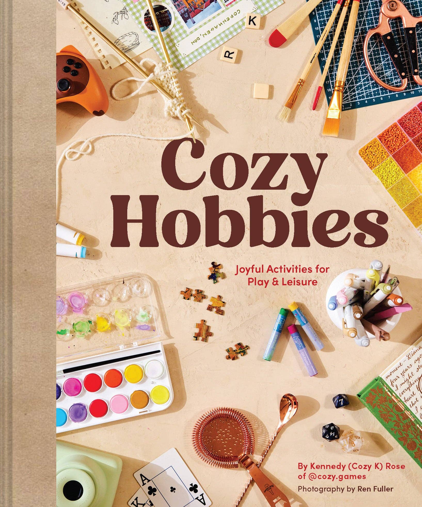 Cozy Hobbies by Kennedy Rose book cover featuring art supplies, yarn, dice, and paints.
