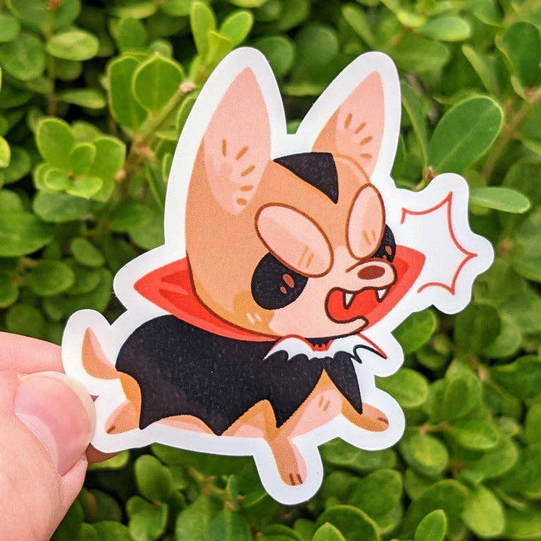 Halloween Puppies Stickers sticker featuring a cartoon vampire dog in a red cape held in a hand.