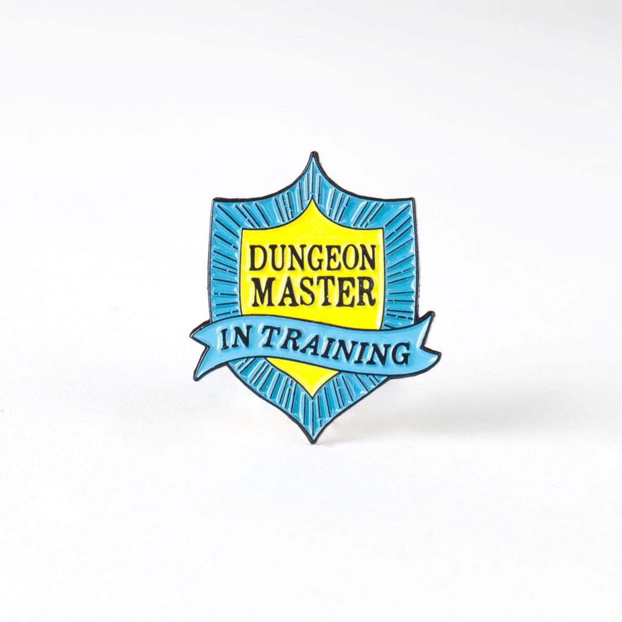 Dungeon Master in Training Badge enamel pin with blue and yellow colors on a white background.
