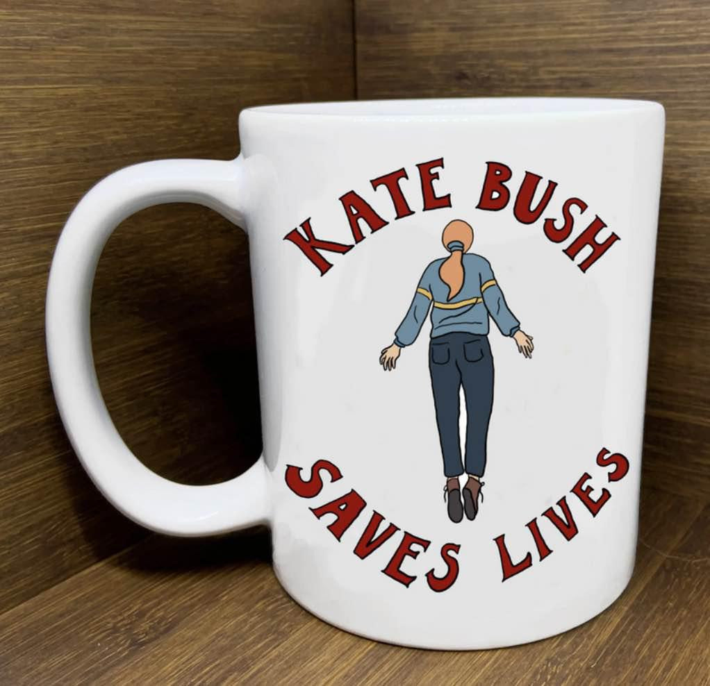 White mug with Kate Bush Saves Lives text and floating woman artwork inspired by Running Up That Hill.