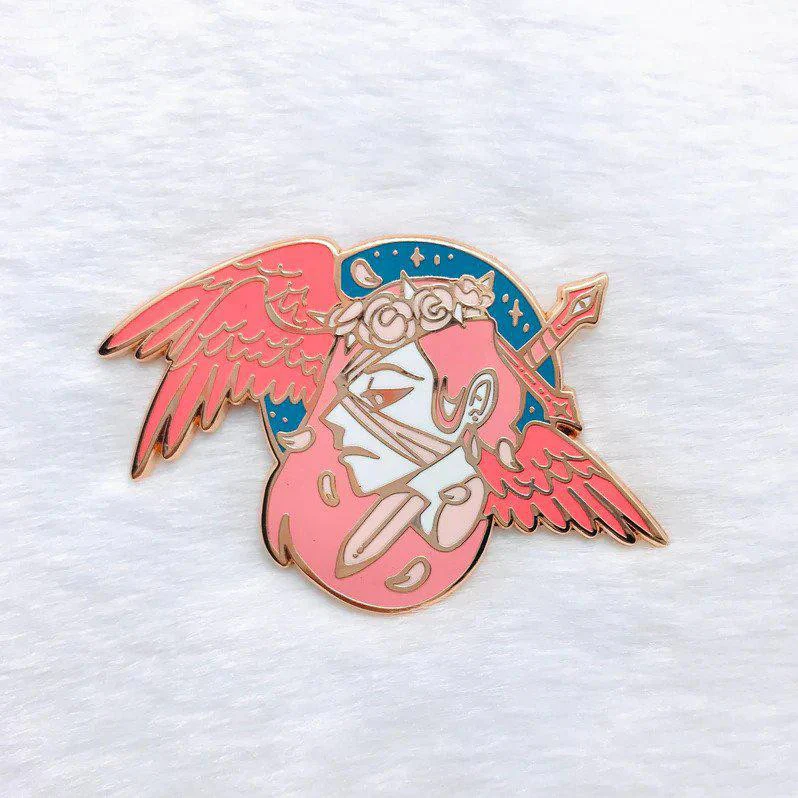 Angel of Judgement rose gold enamel pin with winged helmet in pink, gold, and blue on white background.