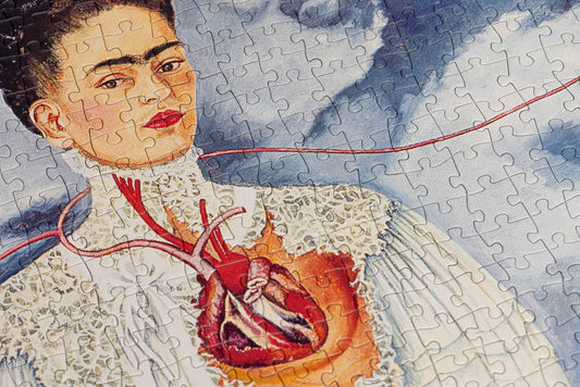 The Puzzles - Frida Kahlo - Two Fridas puzzle featuring a woman with an exposed heart on a cloudy blue background.