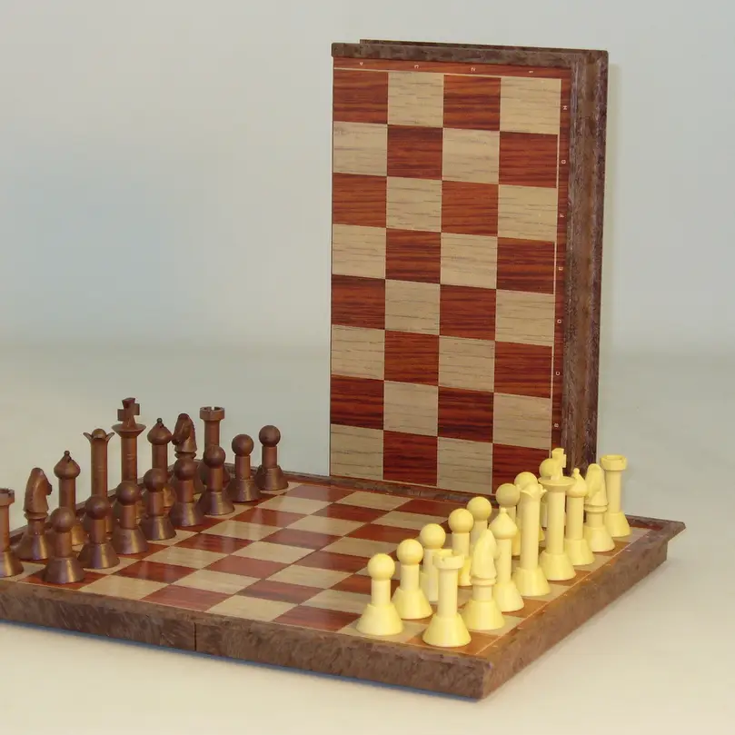 Folding Woody Magnetic Chess Set with wood-tone and cream pieces on a folding chess board.