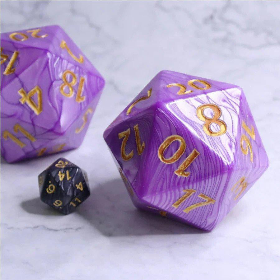 Three 55mm Titan D20 dice, Purple Pearl color with gold numbers, on a light marble surface.