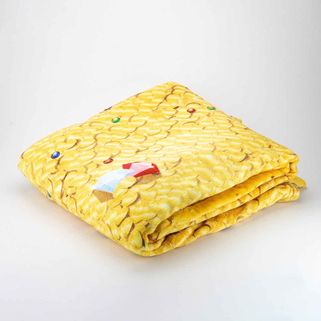 Folded yellow Treasure Hoard Blanket by Tentacle Kitty featuring gold coins and colorful accents on a white background.