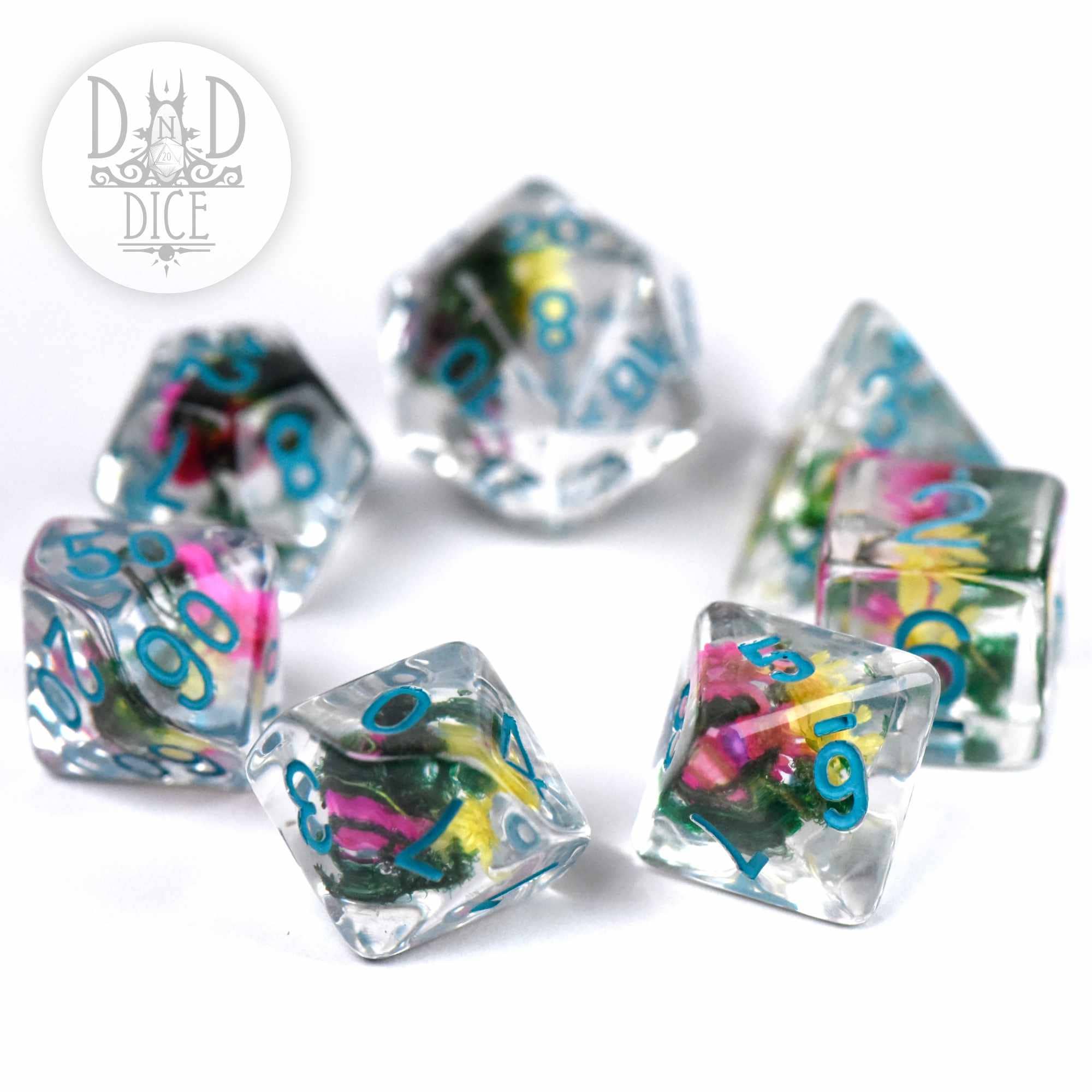 Vintage Bloom 7-piece D&D dice set with colorful flowers in clear resin and blue numbers on a white background.