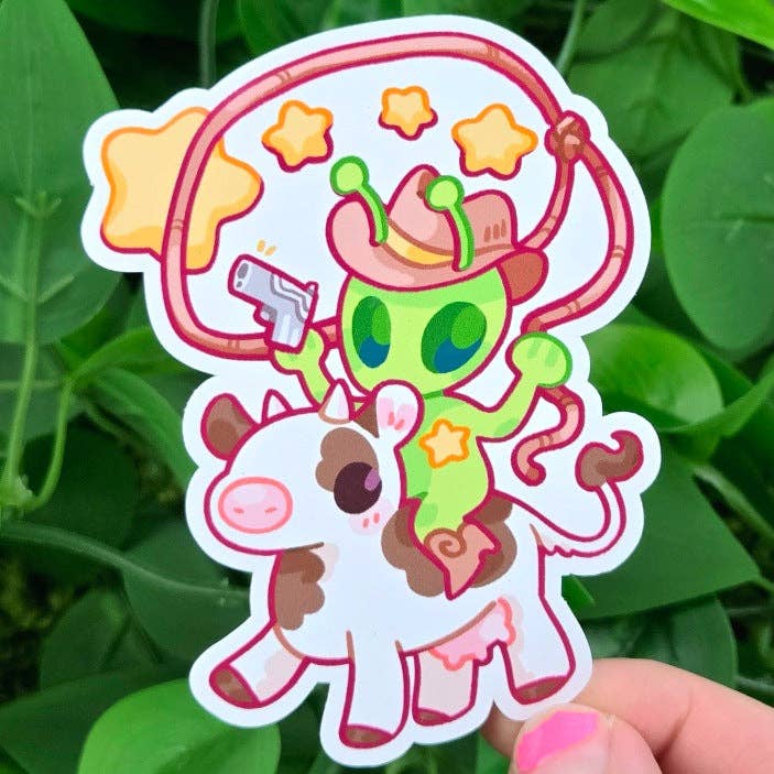 Sticker sheet with cartoon alien in a cowboy hat riding a cow, surrounded by stars.