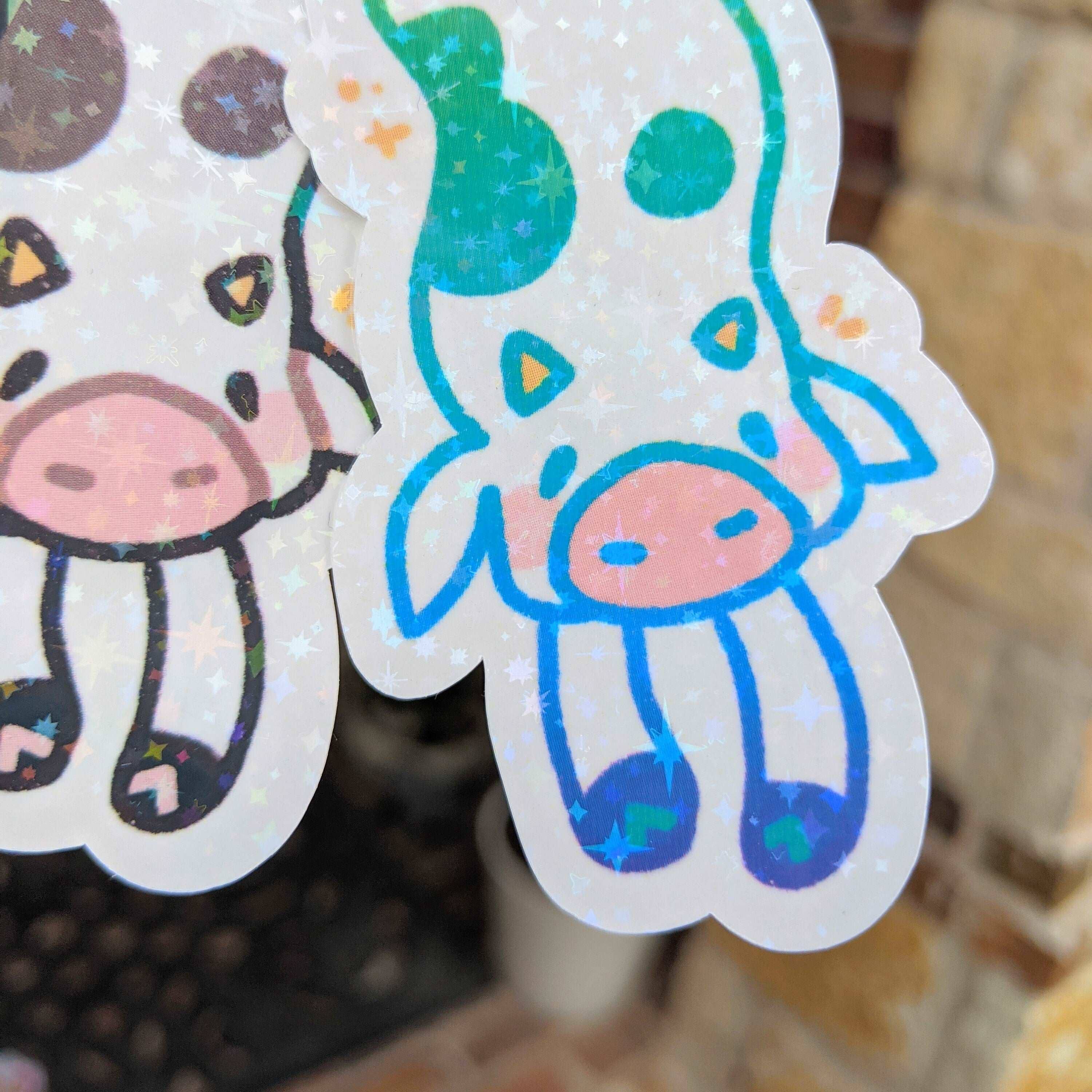 Two waterproof sparkly long cow stickers, one black-spotted and one green.