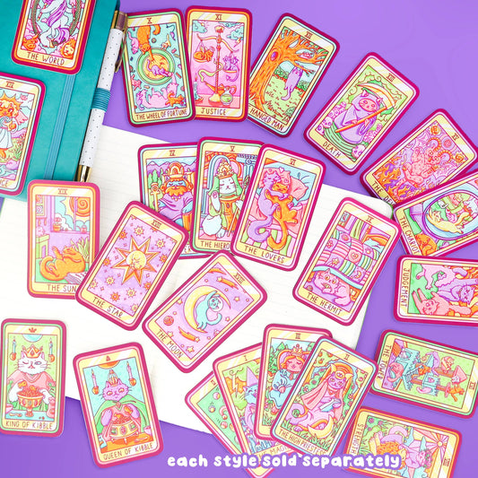 Wheel of Fortune Cat Major Arcana tarot sticker, cat tarot cards, notebook, and pen on a purple surface.