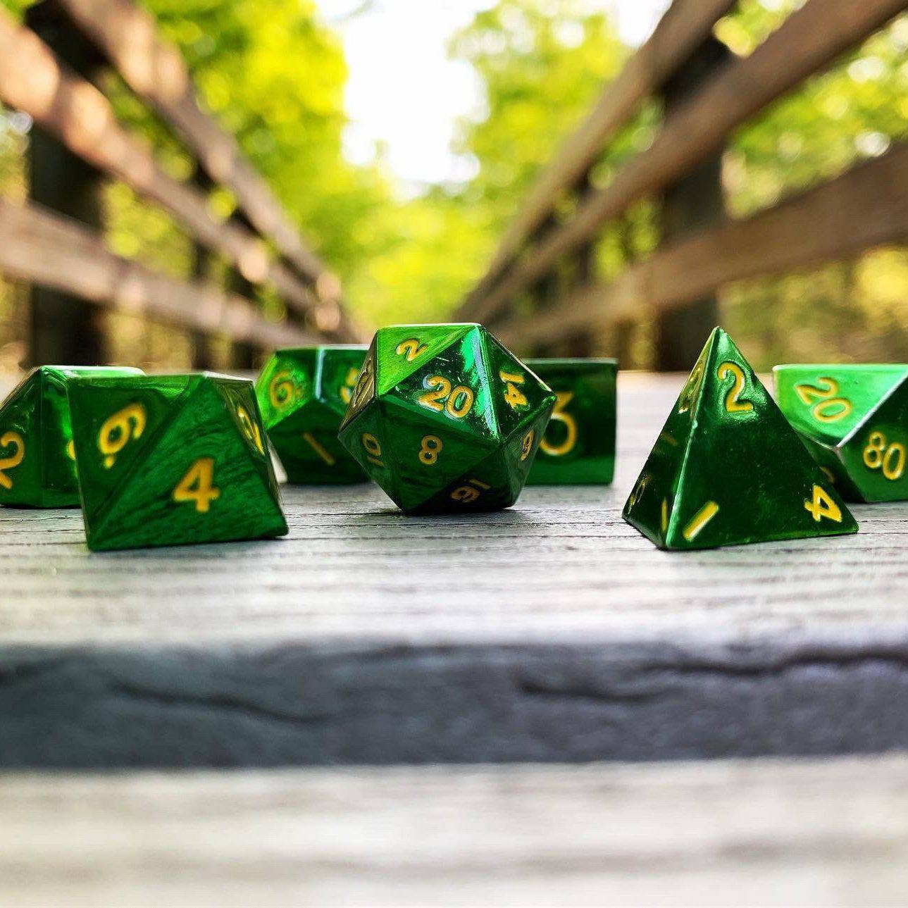 The Goblin Horde 7 Piece Metal D&D RPG Dice Set with yellow numbers displayed on a wooden bridge.