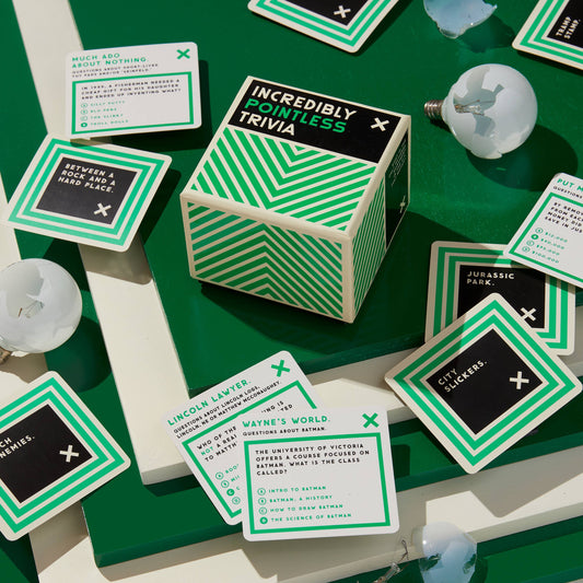 Incredibly Pointless Trivia cube with trivia cards and broken bulbs on a green surface.