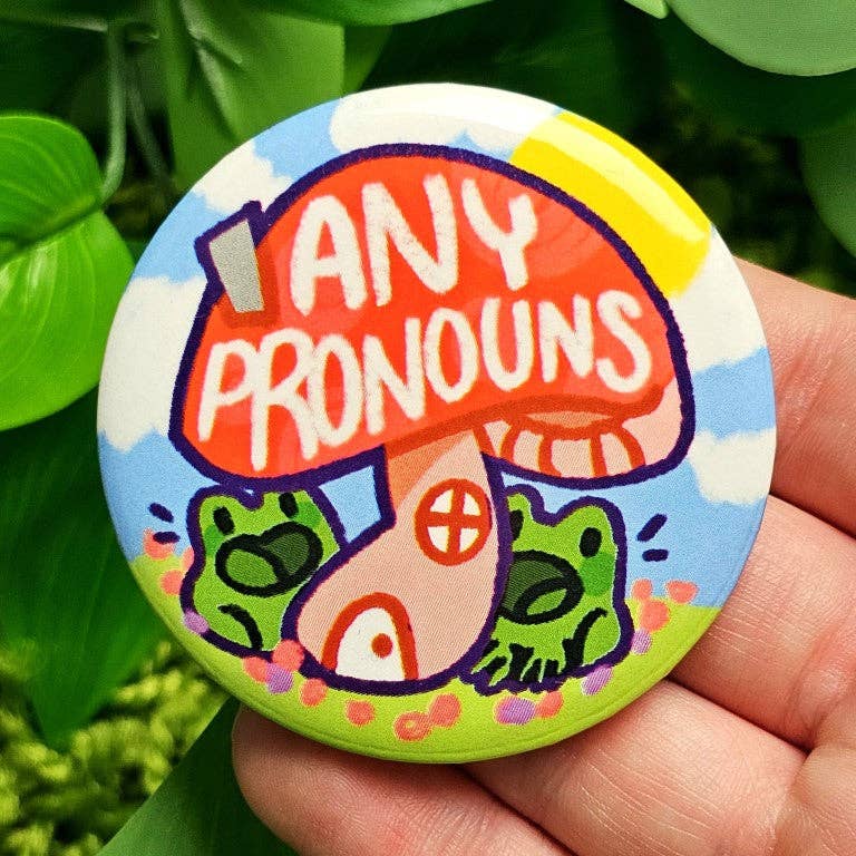 Pronoun Frog Mushroom Large Button with ANY PRONOUNS text held in a hand.