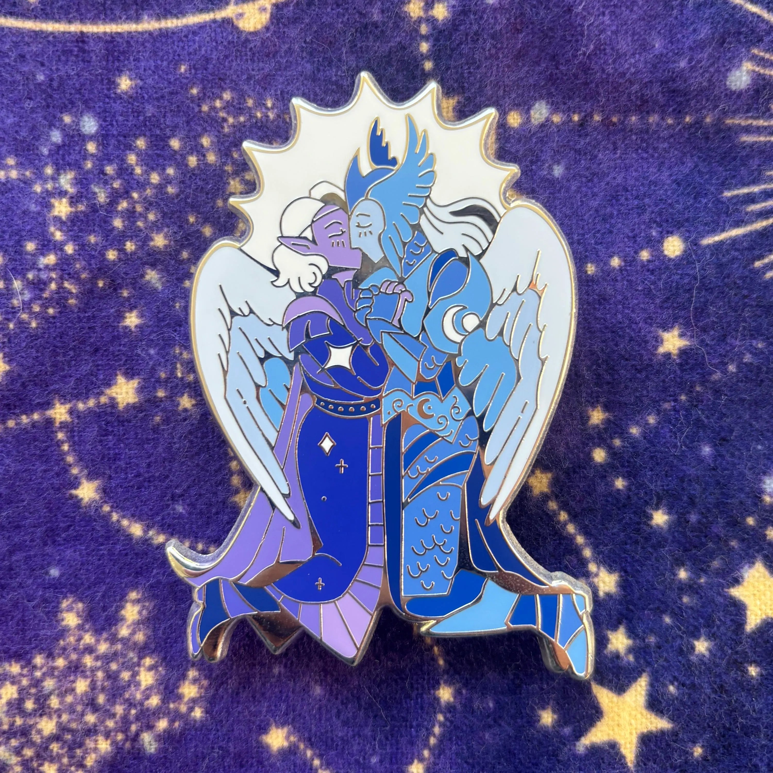 The Aylin and Isobel Pin featuring two armored, winged figures embracing under a starry purple sky.