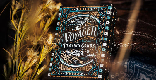 Voyager Playing Cards deck displayed on grass and patterned fabric outdoors.