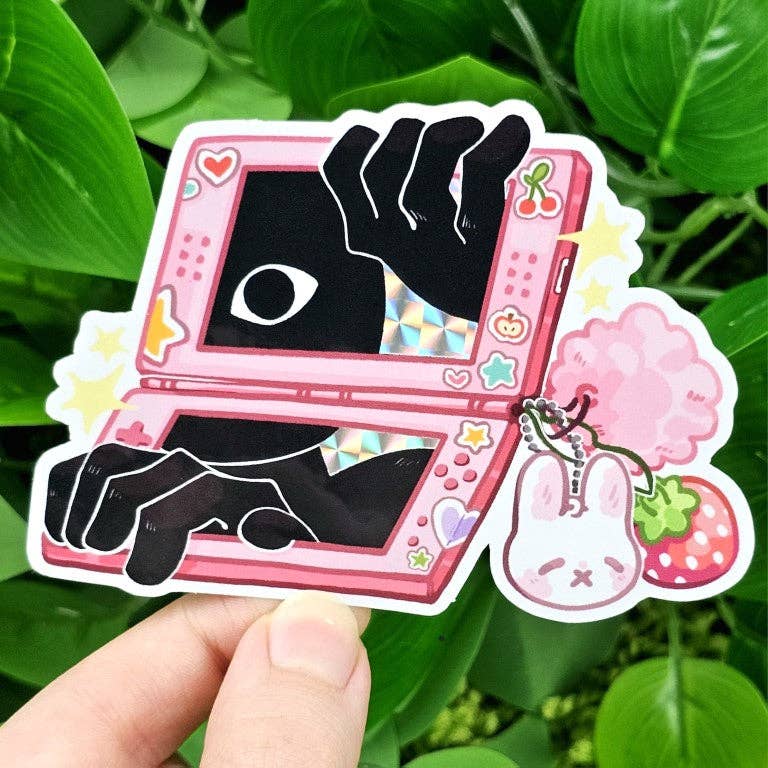 Game console stickers with black hands, an eye, and pink DS charms.