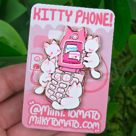Enamel pin of white cats playing with a pink flip phone; displayed on backing card labeled KITTY PHONE.