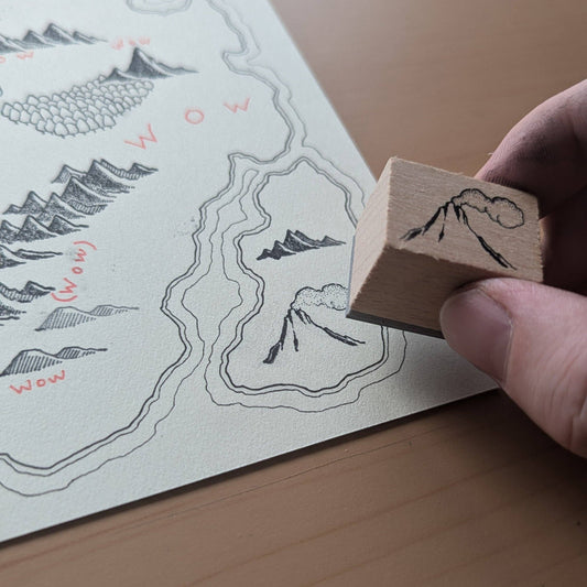 Map stamp kit in use to add a mountain feature to the Blank Map Workbook displaying drawn and stamped elements.