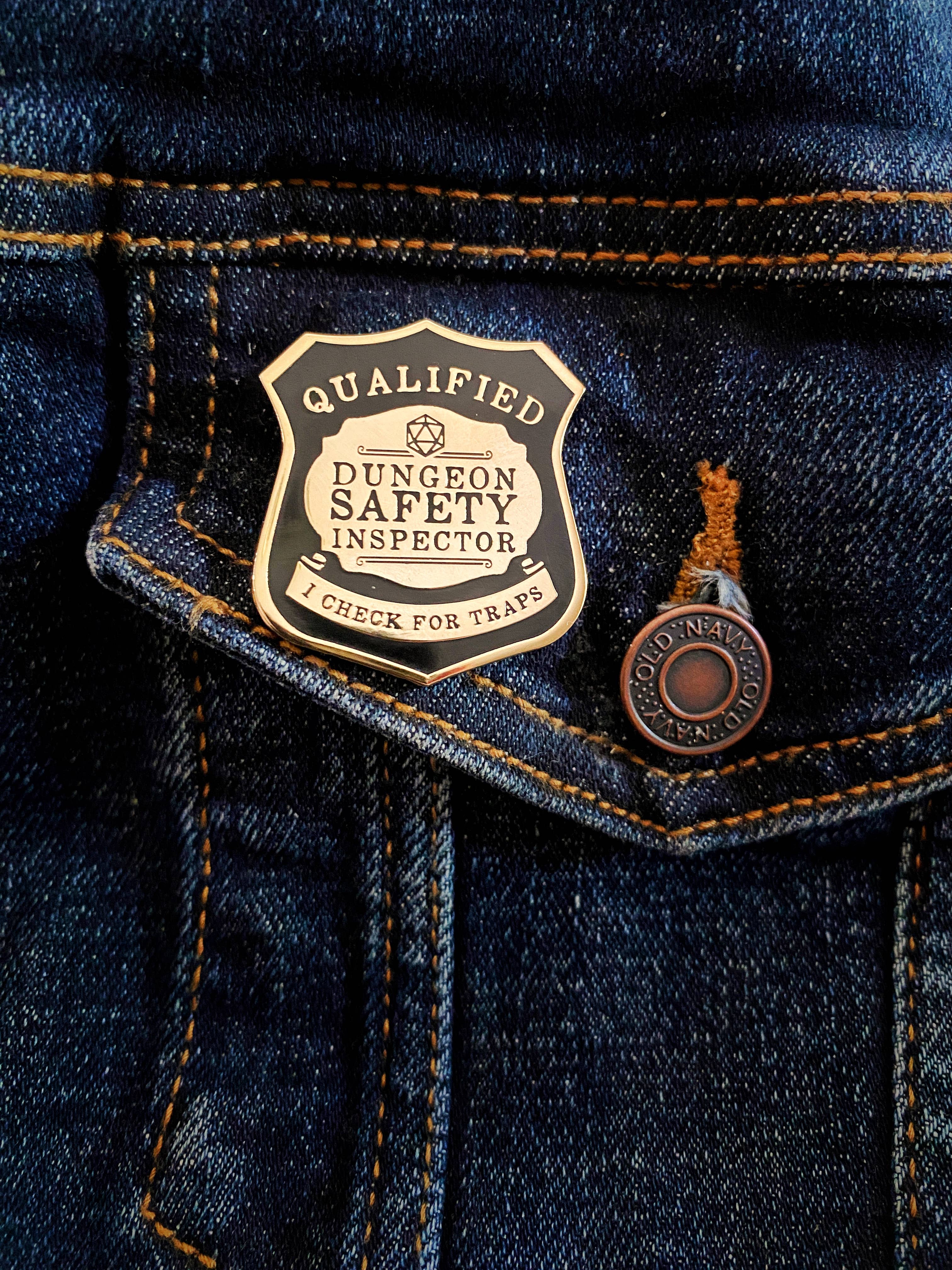 Dungeon Safety Inspector Pin - D&D Enamel Pin attached to the pocket of blue denim jeans near the stitching.