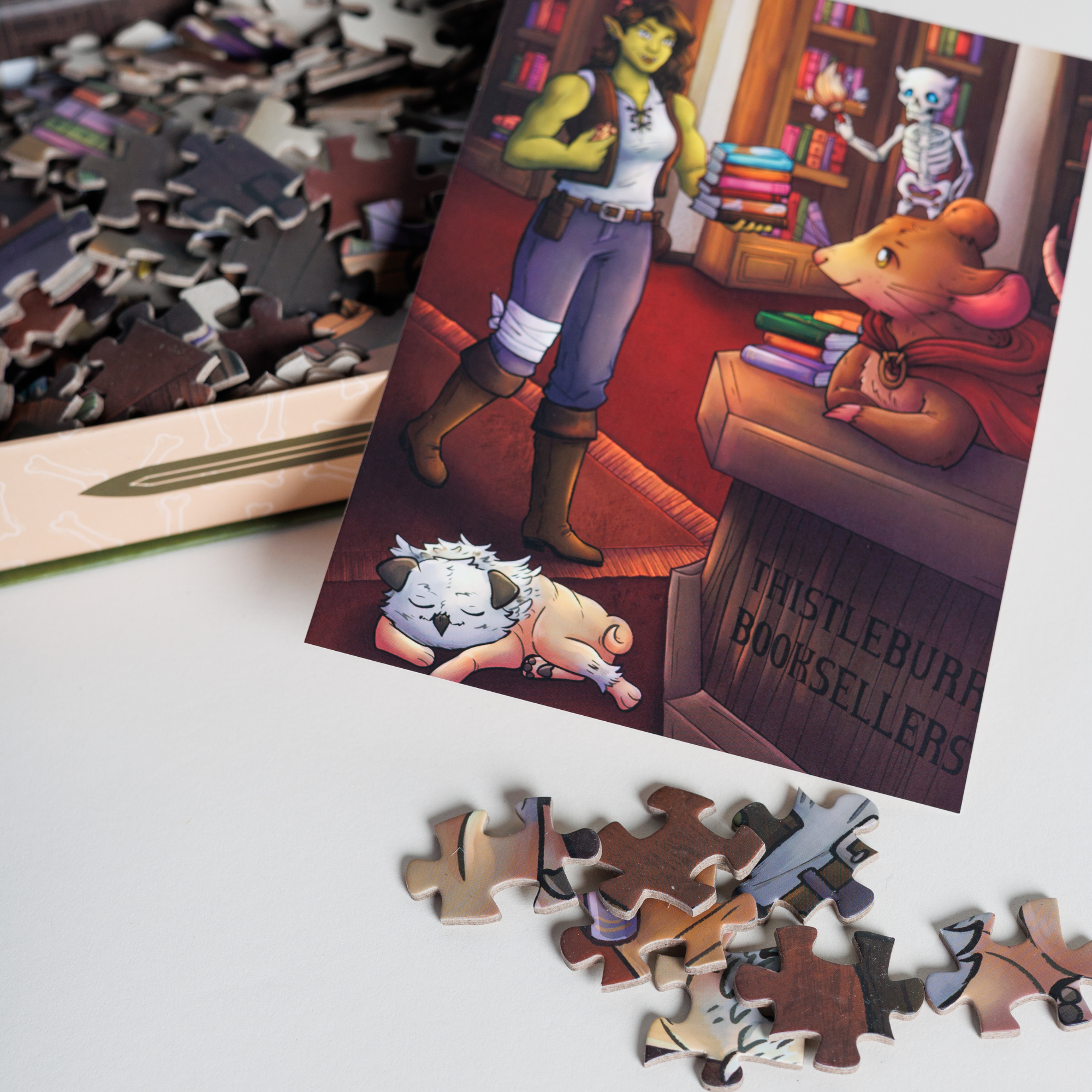 The Thistleburr Bookshop Keepsake Puzzle with fantasy characters, packaged in a book-shaped box.