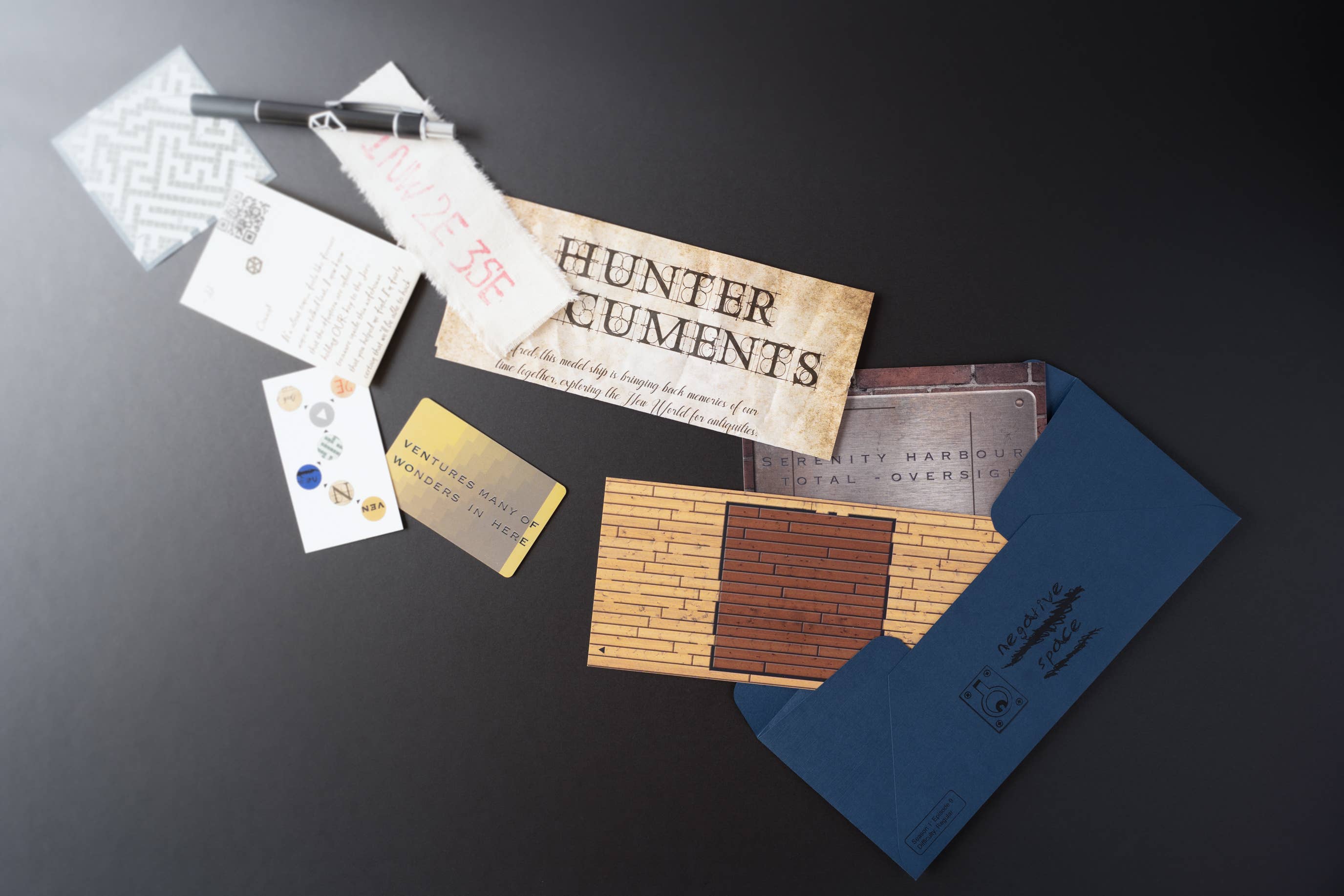 Pen, cards, and Hunter Documents from Family Secrets Episode 9 beside a blue envelope on a dark surface.