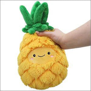 A hand holds the 7-inch Mini Comfort Food Pineapple plush with a smiling face.