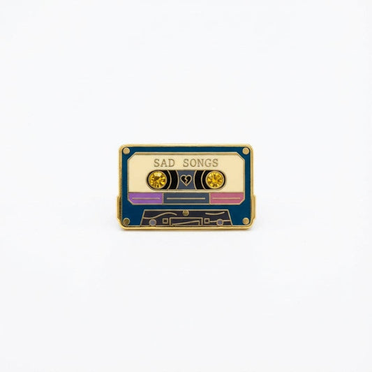 Sad Songs pin (new variant) shaped like a cassette tape with SAD SONGS text, a heart, and two yellow crystals.