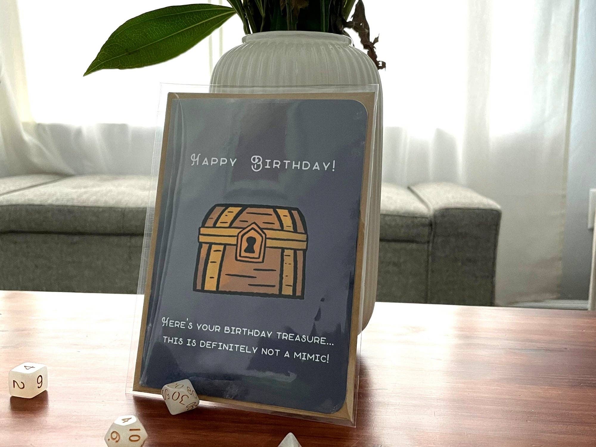 Not A Mimic Birthday Card featuring a treasure chest and dice on a table.