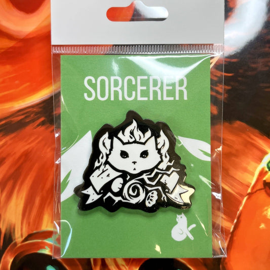Sorcerer enamel pin featuring a cat wizard holding a scroll, displayed on green backing card in clear packaging.