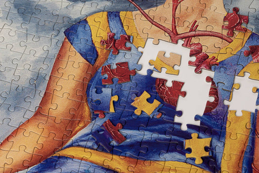 Frida Kahlo Two Fridas puzzle featuring a woman in blue and yellow with missing chest pieces.
