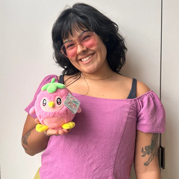 Snacker-sized Strawberry Penguin Alter Ego Squishable plush held by a person with pink sunglasses.