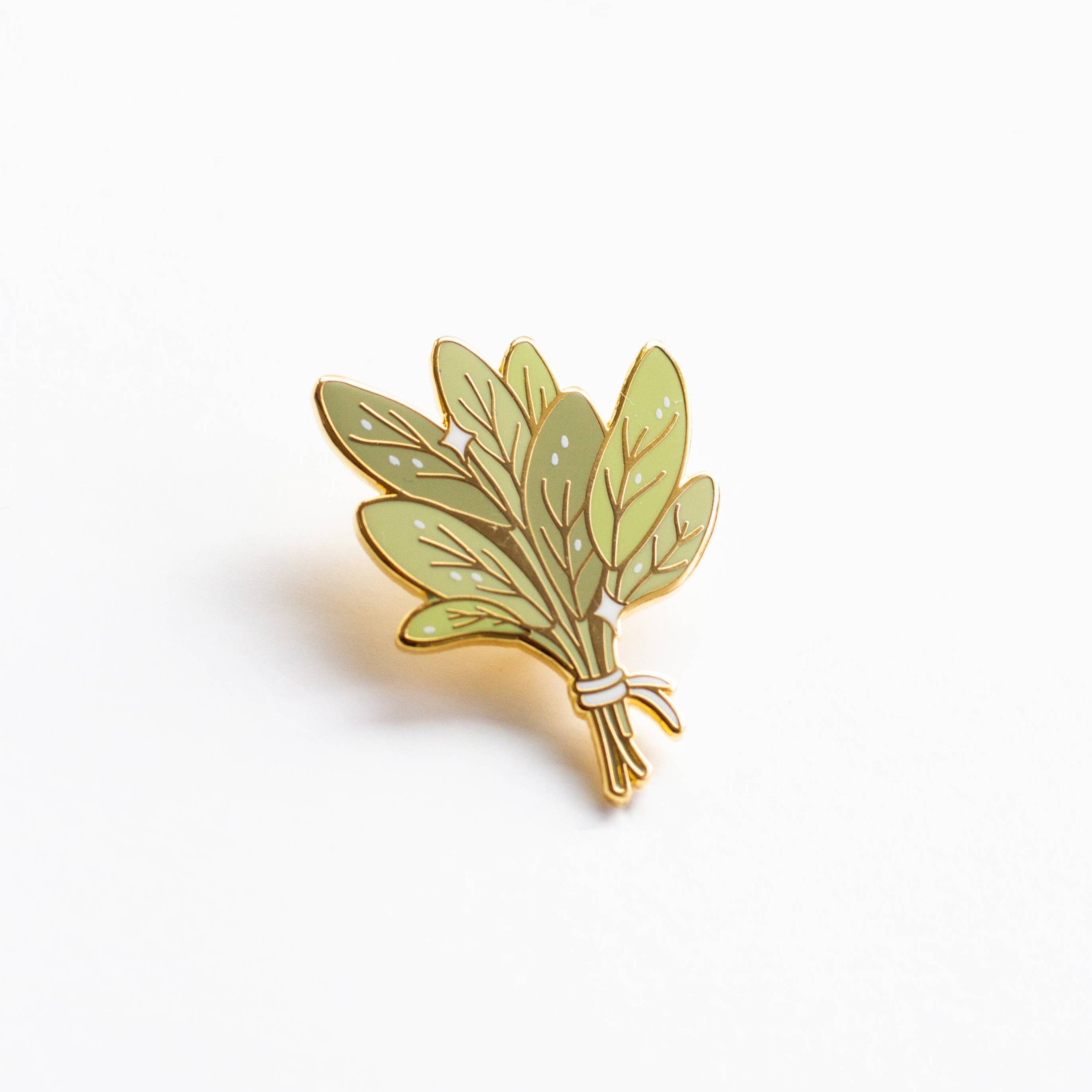 Bundle of Sage enamel pin with gold-edged green leaves tied by white string.