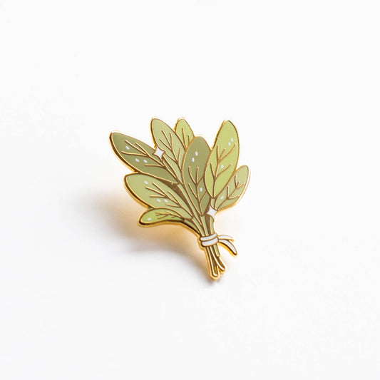 Bundle of Sage enamel pin with gold-edged green leaves tied by white string.