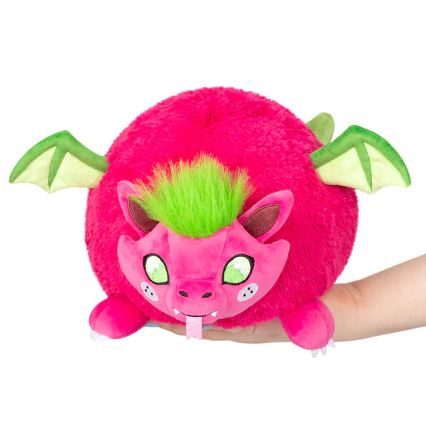 Mini Squishable Dragon Fruit plush, round and pink with green wings, green hair, and a face, held in one hand.